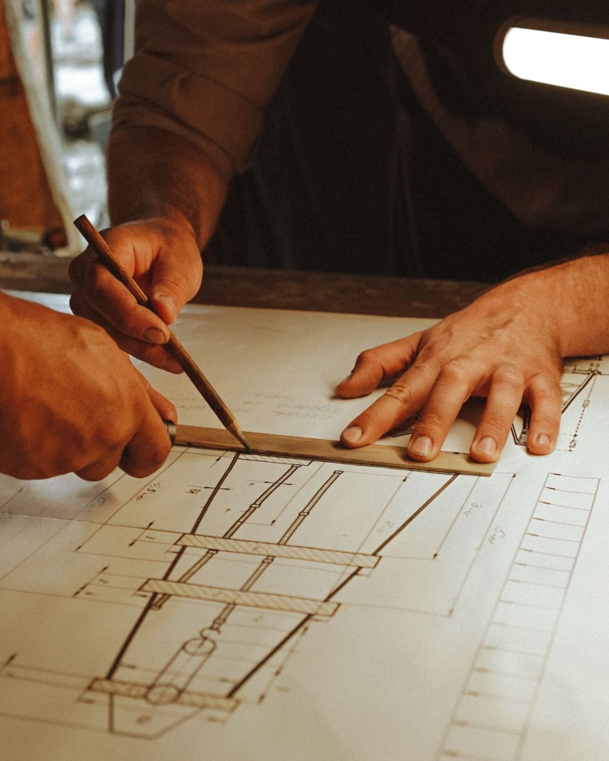 Architect's hands marking a floor plan with a pencil and ruler