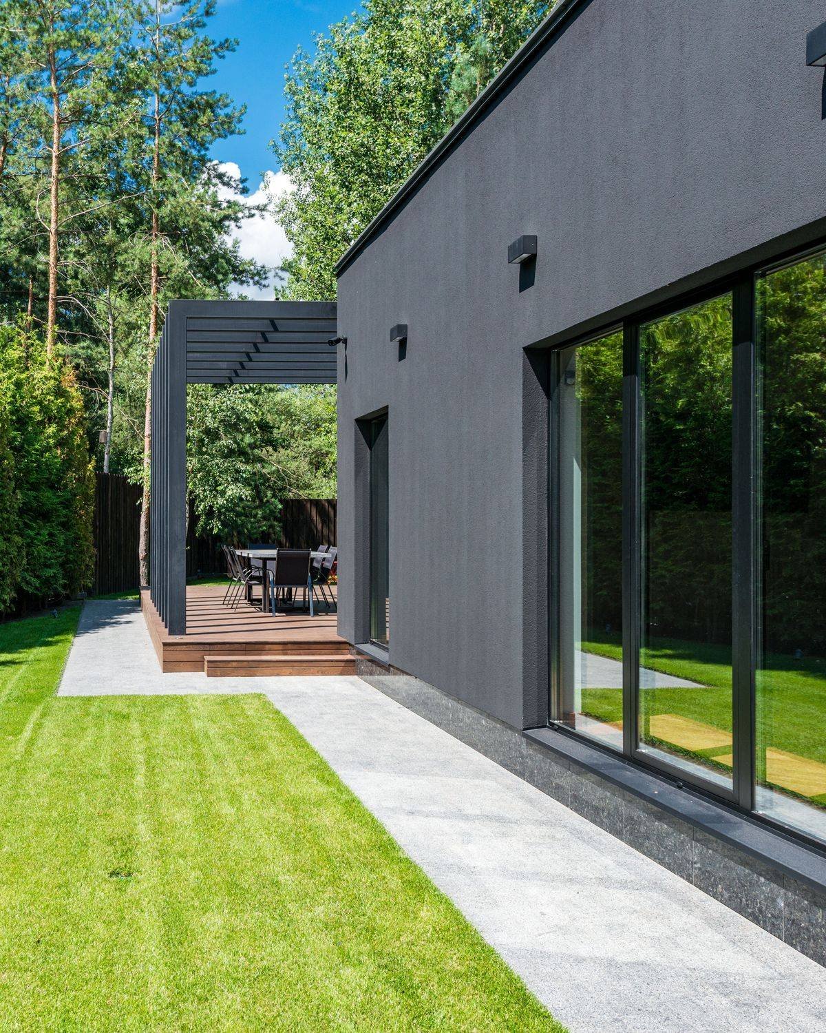 Modern dark-clad residence with large glass doors opening onto a lawn